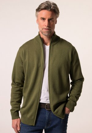 Olive green zip-up cardigan made of textured knit fabric, featuring a high collar, ribbed cuffs, and hem. Worn over a white t-shirt.
