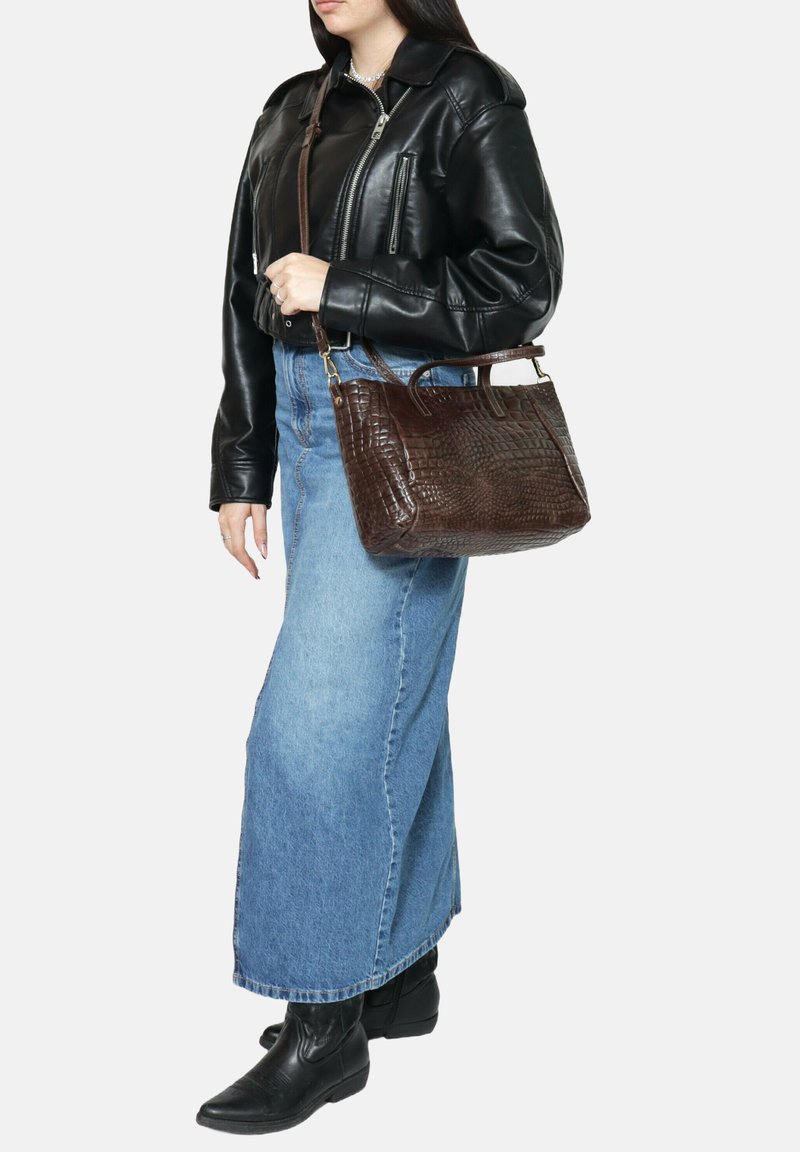 Borsa croc-embossed marrone con manici corti e tracolla removibile. Abbinata a una giacca di pelle nera e una minigonna in denim blu.
