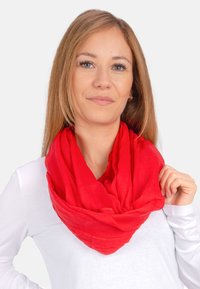 Red infinity scarf, soft lightweight fabric, smooth texture, draped design, layered appearance, worn over a white shirt.