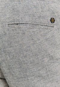 Gray-textured fabric with a subtle plaid pattern. Features a back pocket and a hexagonal logo accent for branding.