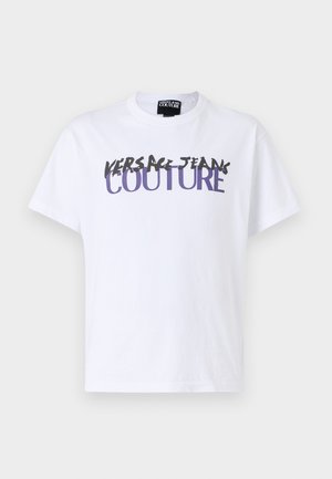 Balts kokvilnas T-krekls ar bold melni un violetiem burtiem "VERSACE JEANS COUTURE", īsajām piedurknēm un apaļo kakla izgriezumu.