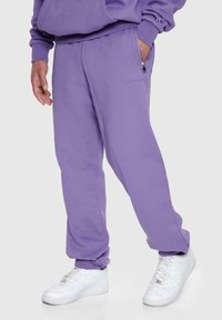 Lilla sweatpants med en afslappet pasform, der har en lynlåslomme og ribbede mansjetter. Fremstillet af blødt bomuldsblandingsmateriale.