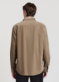 Camicia marrone con bottoni dalla texture liscia, presenta un colletto e maniche lunghe, cuciture visibili e un design con orlo arrotondato.