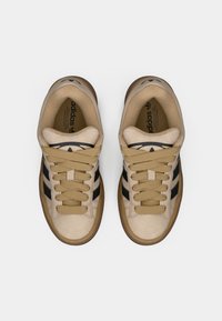 Μπεζ αθλητικά παπούτσια με μαύρες ρίγες, κορδόνια και λογότυπο. Διαθέτουν υλικό άνω μέρους με υφή και σόλα από καουτσούκ τύπου τσίχλας, με στρογγυλεμένη μύτη.