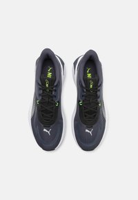 Pantofi sport de culoare gri închis cu accente negre, superior din plasă, talpă albă și șireturi neon verzi vibrante, având un logo pe lateral.