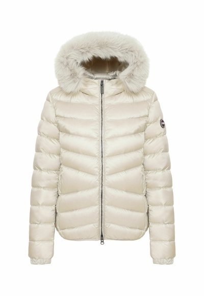 Veste d'hiver matelassée de couleur crème avec une fermeture éclair à l'avant et une capuche doublée en fourrure, avec un petit patch logo rond sur la manche gauche.
