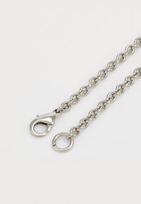 Cadena de metal plateado con eslabones entrelazados, que cuenta con un cierre de resorte y un anillo redondo en un extremo. Textura suave y acabado pulido.