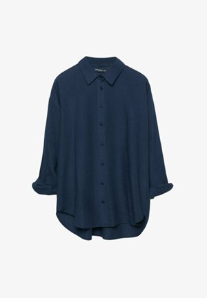Temno modra srajca z gumbom in klasičnim ovratnikom, dolgi rokavi so zasukani, mehka tekstura in sproščen kroj s rahlo ukrivljenim robom.