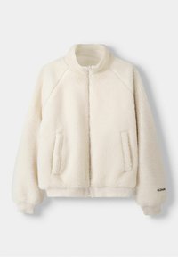 Chaqueta de forro polar en blanco roto con un alto cuello, cierre de cremallera frontal, mangas raglán y bolsillos laterales; presenta una superficie suave y texturada.