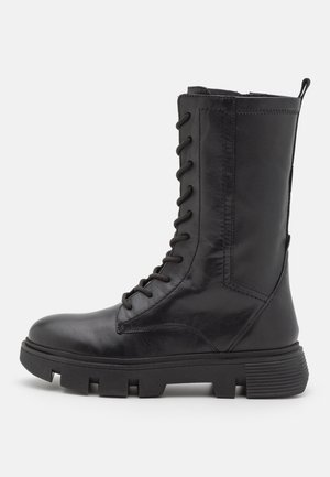 Botas de cuero negro hasta la rodilla con cordones prominentes, acabado texturizado, suela de goma y tacón reforzado para mayor durabilidad.