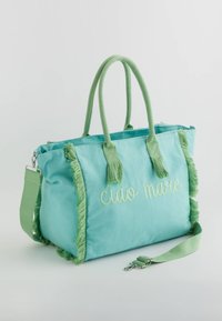 Groene katoenen tas met franjes, twee handvatten aan de bovenkant en een afneembare schouderband. "Ciao mare" geborduurd in lichtgroen op de voorkant.