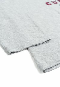 T-shirt in cotone grigio che mostra la texture del tessuto, con maniche corte e scollo rotondo. Caratterizzato da cuciture sottili e orlo ripiegato.