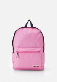 Zaino rosa dalla forma arrotondata. Realizzato in tessuto, presenta una tasca frontale con zip, dettagli in blu navy e un logo bianco. Due spallacci regolabili.