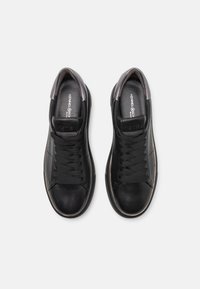 Paire de baskets en cuir noir à lacets, bouts arrondis et semelles intérieures de marque, vues de dessus sur fond blanc.