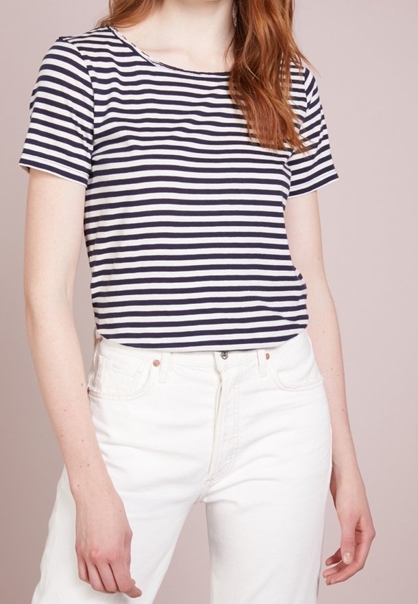 Marinblå och vita randiga t-shirt med rund halsringning och korta ärmar, matchad med vita högmidjade jeans. Mjuk bomullstyg.