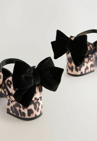 Sorte fløjl platform sandaler med store sløjfer, prydet med leopardmønster på en tekstureret bund og metallisk accent på stroppen.