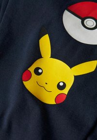 Navyblått fabric har ett stort gult Pikachu-ansikte med röda kinder och framträdande svarta ögon, kombinerat med en design av en röd och vit Poké Ball.