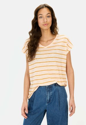 Kortærmet V-hals top i lys beige med orange vandrette striber; parret med højttaljede blå denimbukser. Blød tekstur.