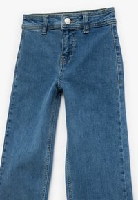 Vaqueros de denim azul con un diseño de pierna recta. Presentan un botón visible, costura superior y costuras de los bolsillos traseros. Acabado lavados clásico claro.