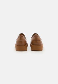 Zapatos de cuero marrón con un acabado liso, diseño de perfil bajo y puntera redondeada. Presentan costuras discretas y una suela de goma sólida.