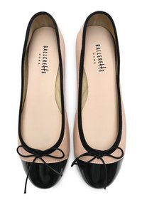 Ballerine con una morbida tomaia in cuoio nude e una punta nera lucida, con un bordo nero e un dettaglio con fiocco annodato sulla parte anteriore.