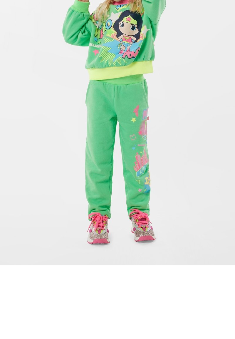 Grøn sweatshirt med grafisk print, matchende grøn sweatpants og pink sneakers med glitrende detaljer. Blød tekstur og afslappet design.