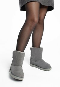 Botines de ante gris con forro de pelo sint�ético, suela de goma plana y un diseño ligeramente ahusado. Llevados con medias opacas negras.