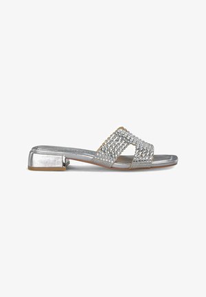 Sandalias planas plateadas que presentan dos correas cruzadas adornadas con brillantes, un tacón bajo y un acabado metálico suave.