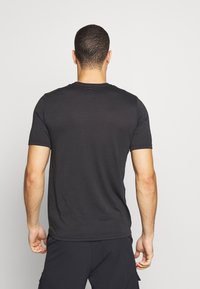 Sort kortærmet t-shirt lavet af glat stof, med rund hals og en afslappet pasform, vist fra ryggen.
