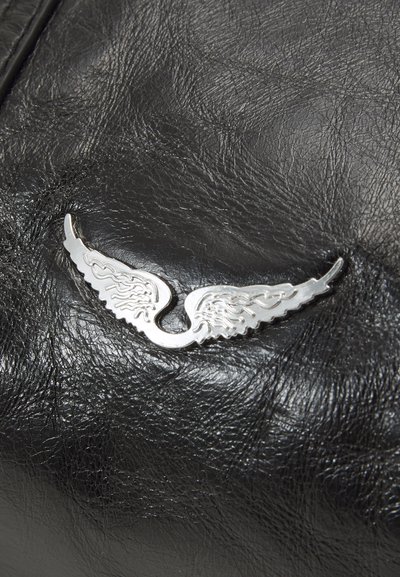 Black leather surface with a textured finish and a prominent silver wing-shaped emblem displaying intricate detailing and curves.