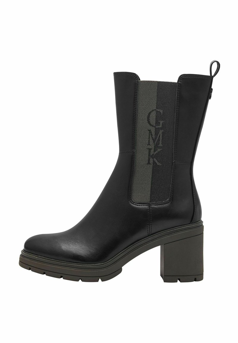 Bottine en cuir noir avec un talon carré, dotée d'un panneau en tissu vert texturé et d'une marque en relief sur le côté.