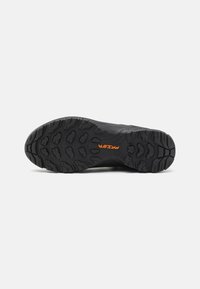 Schwarze Sport-Schuhsohle mit einem robusten Profilmuster für Traktion, mit einem orangefarbenen "PRISHT"-Logodetail in der Nähe der Mittelsohle.