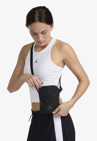 Geantă crossbody din nylon negru cu buzunar cu fermoar, având un accent subtil cu logo. Curea reglabilă și design plat pentru portabilitate.