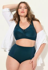 Reggiseno teal con design testurizzato e leggera lucentezza, caratterizzato da un dettaglio con fiocco frontale. Slip teal a vita alta con finitura liscia e accenti a motivo.