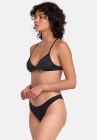 Čierny bikiny set s trojuholníkovým vrchom a tenkými ramienkami a spodným dielom s nízkym pásom. Hladká textúra a minimalistický dizajn.