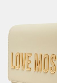 Borsa color crema con scritta in oro embossata "LOVE MOS," dal texture liscia e bordi arrotondati.