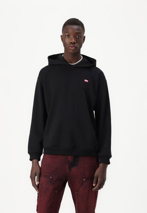 Black hoodie with a front pocket and a small red brand logo. Pairs with red textured pants. Smooth fabric, relaxed fit.