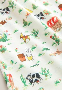 Tissu en coton à motifs présentant des animaux et des cactus aux couleurs vives, y compris un ours, un cheval, un lapin et une vache sur un fond blanc.