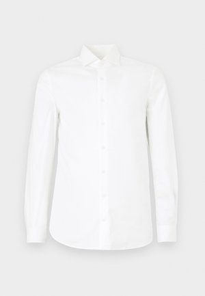 Biała, długa koszula z długim rękawem z gładkiej bawełny. Posiada stożkowy kołnierzyk, pełne zapięcie na guziki oraz lekko zwężoną talię.