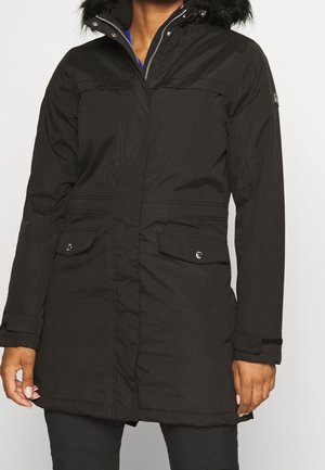 Manteau d'hiver noir avec capuche bordée de fourrure, fermeture éclair à l'avant et poches à pression, porté par une personne du cou jusqu'à mi-cuisse, mains visibles sur les côtés.