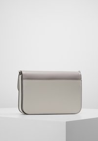 Šedá kožená kabelka s klopovým uzavíráním, obdélníkový tvar, hladký povrch a čisté linie. Obsahuje jemné prošívání a štíhlý profil.