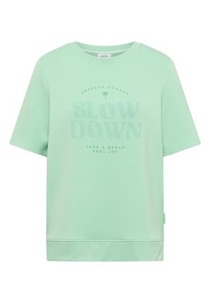 Chemise à manches courtes vert menthe avec encolure et ourlet côtelés, texte imprimé "SLOW DOWN" avec un palmier et les phrases "EMBRACE CHANGE" et "TAKE A BREAK FEEL JOY."