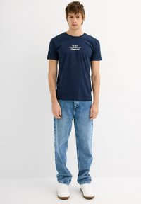 Camiseta de algodón azul marino de manga corta y cuello redondo; presenta el texto blanco "NO TOCAR SIN PERMISO" en la parte frontal.