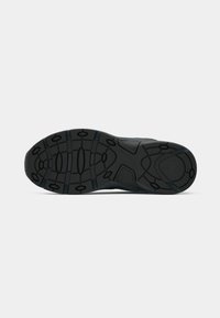 Sole de pantof sport negru, cu o suprafață din cauciuc texturat. Prezintă un model al tălpii format din ovale și linii pentru tracțiune și aderență.