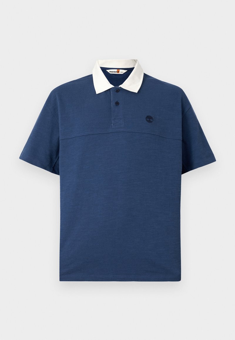 Polo-shirt bleu marine avec un col blanc, manches courtes, patte de boutonnage à deux boutons et un petit logo noir sur la poitrine. Texture de tissu douce.