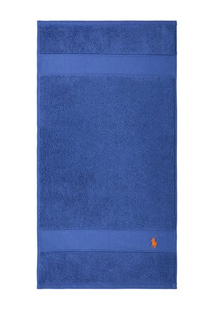 Serviette rectangulaire bleue avec sections texturées et un petit logo de joueur de polo brodé en orange dans le coin inférieur droit.