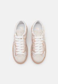 Le sneakers presentano un design beige e bianco con un motivo in pelle di serpente testurizzata, lacci bianchi e una punta liscia. Accento del logo dorato sulla linguetta.