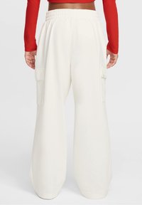 Široké cargo kalhoty v krémové barvě, s jemnou texturou, elastickým pasem a postranními kapsami. Design nabízí uvolněný střih.