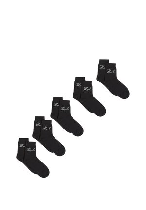 Calcetines tobilleros negros fabricados con tejido suave. Presentan una marca gris claro en el costado. Cinco pares exhibidos en fila.