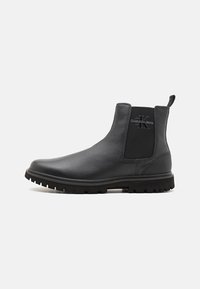 Zwarte leren Chelsea-boots met een gestructureerde bovenkant, elastische zijpanelen, een aantreklip en een robuuste rubberen zool. Calvin Klein-logo aan de zijkant.